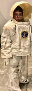 A young male student in a white space suit and helmet