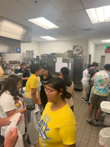 blind students stand in a big commercial kitchen before starting to cook.