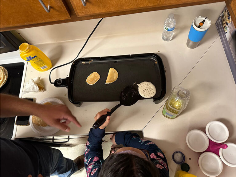 A young girl flips pancakes on a griddle at the ecc summer camp in Brownsville June 2023