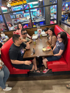Students sit at a booth in a restaurant with a birthday cheesecake at the ecc summer camp in Brownsville 2023