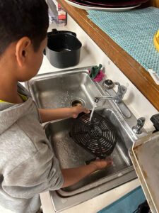 boy washes airfryer in a sink at the ecc summer camp in Brownsville 2023